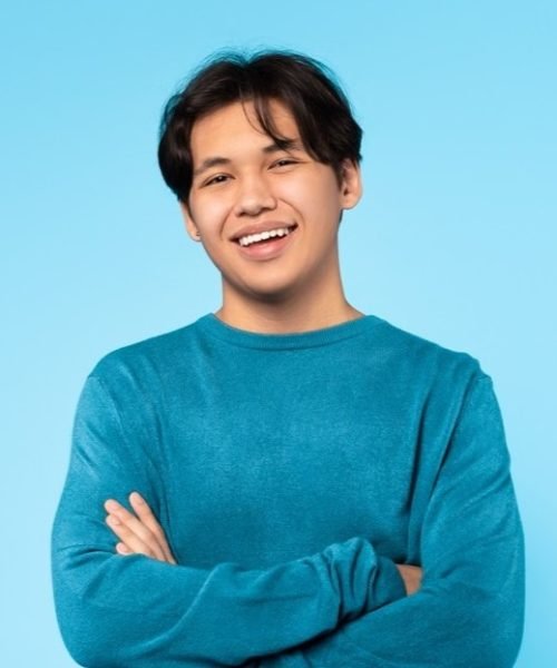 Confident Japanese Teen Guy Posing Crossing Hands Over Blue Background
